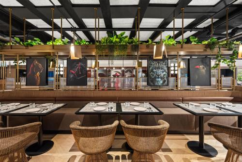 a restaurant with tables and chairs and plants at Radisson RED Auckland in Auckland