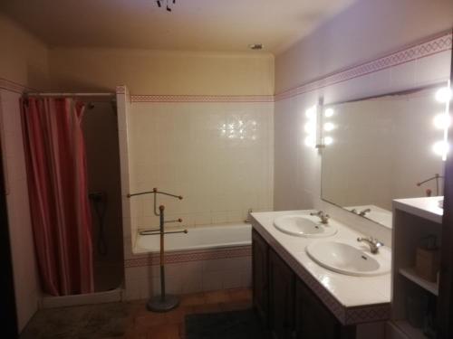 a bathroom with a tub and two sinks and a shower at Gîte de la glycine in Marmande
