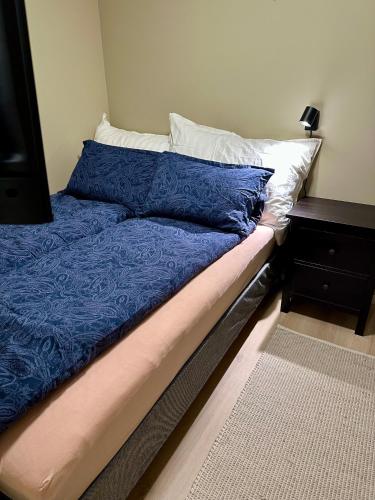 een bed met blauwe lakens en witte kussens erop bij Modern studio apartment with wood-fired sauna in Bjørkheim