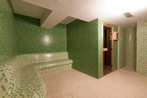 a bathroom with green walls and a bath tub at Golden Tulip Ana Dome Hotel in Cluj-Napoca