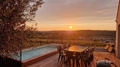 un ponte con tavolo e sedie e una piscina di La villa Sunset a Trélissac