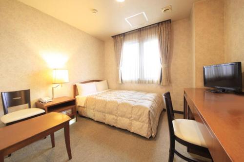 a hotel room with a bed and a desk at Shinmatsudo Station Hotel in Matsudo