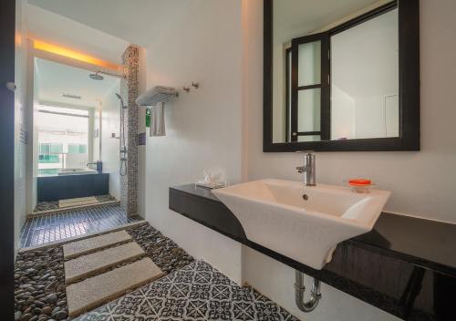 a bathroom with a sink and a shower with a mirror at The Old Phuket - Karon Beach Resort in Karon Beach