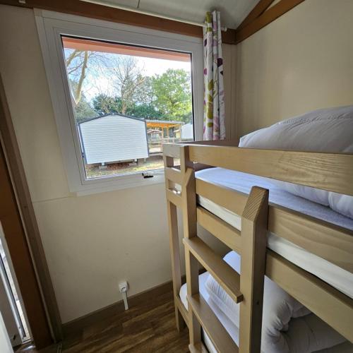 a bedroom with a bunk bed and a window at Chalet KABANA in Saint-Hilaire-de-Riez