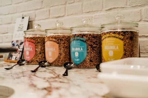 Vier potten granola met lepels op het aanrecht. bij Hotel Huis van Bewaring - Bijzonder boutique hotel in historisch pand in Almelo