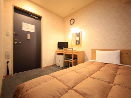 a bedroom with a bed and a desk and a door at Hachioji Urban Hotel in Hachioji