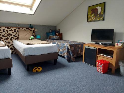 a bedroom with two beds and a flat screen tv at Boerderij Hazenveld in Kockengen