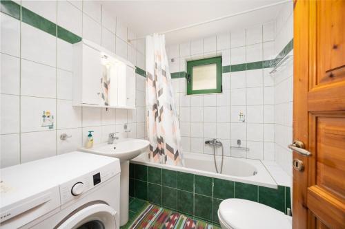 a bathroom with a sink and a tub and a washing machine at Villa Martha in Ieromónachos