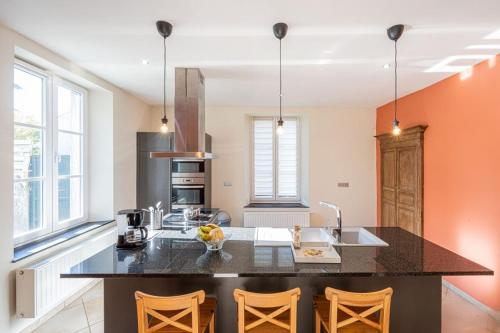a kitchen with a black counter top and orange walls at A Fleur de l'Eau Blanche gite de caractère in Chimay