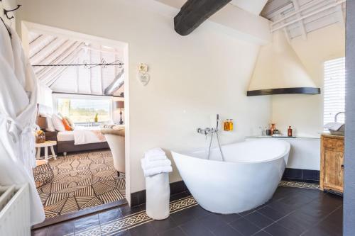 a bathroom with a tub and a bedroom at B&B Kasteel Maurick in Vught
