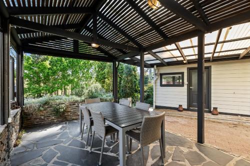 a patio with a wooden pergola and a table and chairs at The Other House in Piccadilly