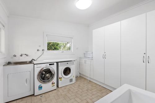 a white laundry room with a washer and dryer at The Other House in Piccadilly