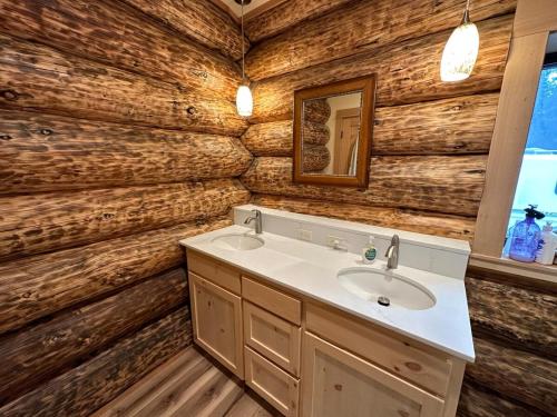 a bathroom with a sink and a wooden wall at Waterfront Log Cabin - Sunriver in Bend