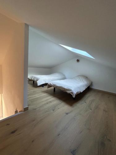 two beds in a room with a ceiling with a light at La maison du Quart - Maison de village in Sommières
