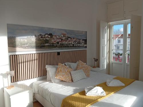 a bedroom with a white bed with a picture on the wall at Casa João Chagas Guesthouse, Constância, By Viva a Vida - Alojamentos e Hotels in Constância