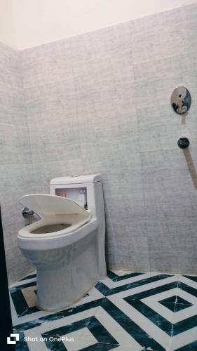 a bathroom with a toilet and a tiled wall at Hotel Aarav Inn in Pānīpat