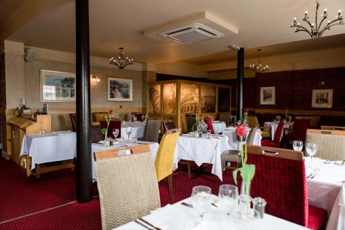 een eetkamer met tafels en stoelen met witte tafelkleden bij Ennios Boutique Hotel in Southampton