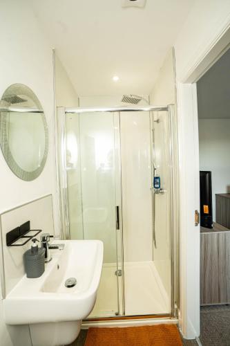 a white bathroom with a shower and a sink at Queens Court Ensuite Studio in Stoke on Trent