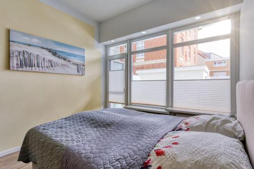 een slaapkamer met een bed en een groot raam bij Alte Teestube 55 in Norderney