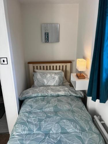 ein Schlafzimmer mit einem Bett mit blauer Bettdecke in der Unterkunft Witz End in Corsham