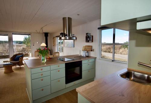 una cucina con mobili bianchi e un forno a piano cottura di Lovely Summer House On Natural Grounds a Frøstrup