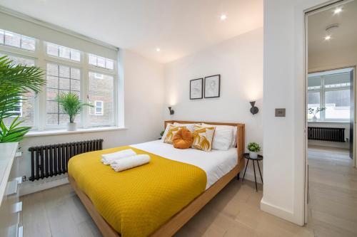 a bedroom with a large bed with yellow sheets at Welcome Shoreditch, 1 Bed 1 Bath London Apartment in Superb Location in London