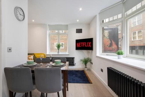 a dining room with a table and chairs and a clock at Welcome Shoreditch, 1 Bed 1 Bath London Apartment in Superb Location in London