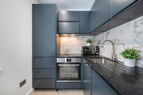a kitchen with blue cabinets and a sink at Welcome Shoreditch, 1 Bed 1 Bath London Apartment in Superb Location in London