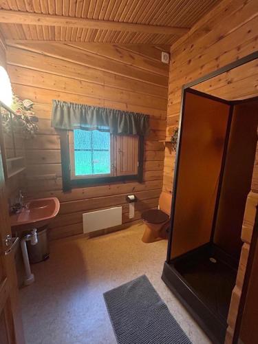 a bathroom with a sink and a toilet and a window at Private Swedish Forest Cabin in Ulricehamn
