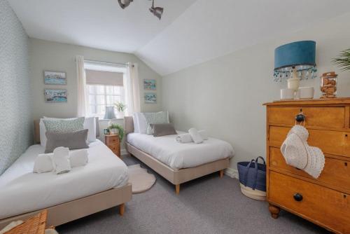 a bedroom with two beds and a dresser at Olive Cottage in Swanage