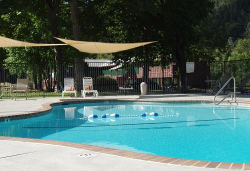 a swimming pool with a umbrella and chairs at Indian Creek Lodge in Douglas City