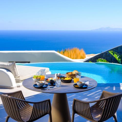 un tavolo con del cibo sopra accanto a una piscina di Secret Path Luxury Villas a Imerovigli