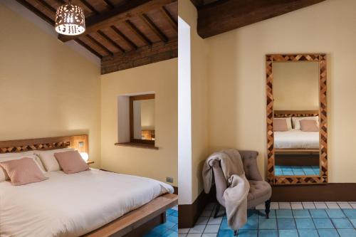 a bedroom with a bed and a chair and a mirror at Le Dimore by Borgo Tessile - Feronia in Orvieto