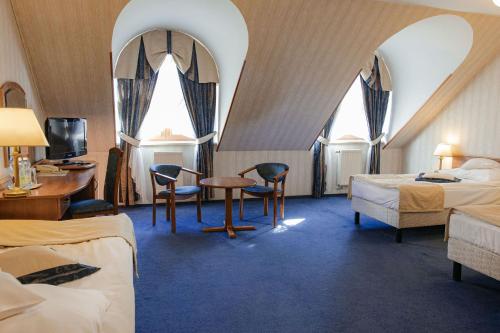een hotelkamer met twee bedden en een tafel en stoelen bij Hotel Basztowy in Sandomierz