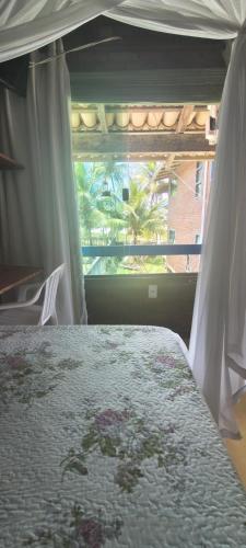a bedroom with a bed with a view of a window at Edícula 2 quartos frente mar in Ilhéus