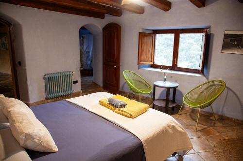 a bedroom with a bed and two green chairs at Mas els Terrats in Susqueda