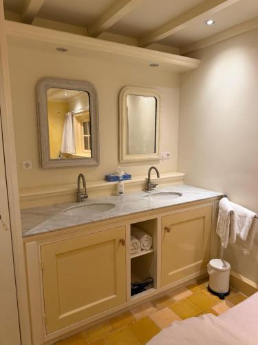 a bathroom with two sinks and a mirror at Cottage Het Beukenootje in Aerdenhout