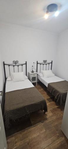 two beds in a room with wooden floors at La vagoneta in Cala
