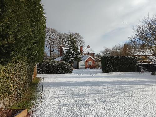 a snow covered street with a house in the background at The Beehive Inn in Bury Saint Edmunds