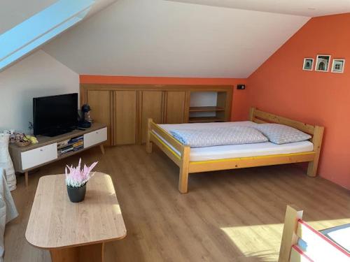a bedroom with a bed and a tv and a table at Pokoj U lesa Zaolší in Vendryně
