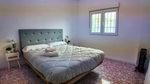 een slaapkamer met een bed met een blauw hoofdeinde en een raam bij Apartalux Playa Arenal in Burriana