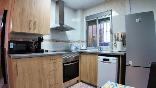 een keuken met houten kasten, een wastafel en een koelkast bij Apartalux Playa Arenal in Burriana