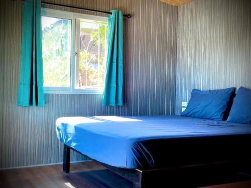 een slaapkamer met een bed met blauwe lakens en een raam bij Sand and Sea Koh Kood in Ko Kood
