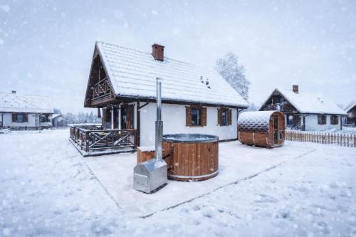 a house with a snow covered yard with a building at Warmia Prestige in Woryty