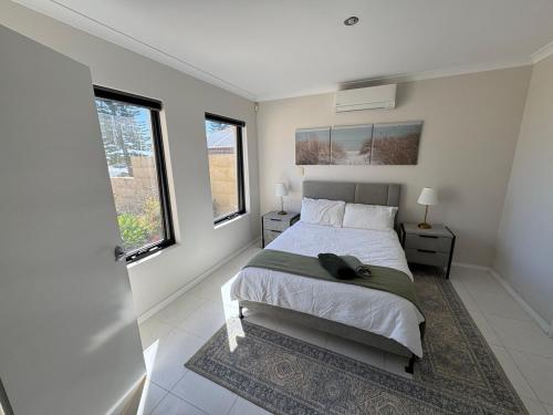 a bedroom with a bed and two windows at Ocean Whisper in Wannanup