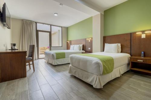 een hotelkamer met twee bedden en een bureau bij Hotel San Agustin Plaza in Latacunga