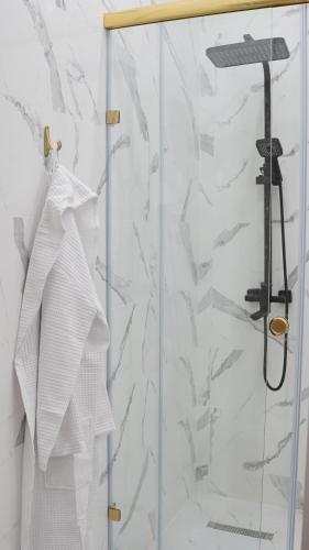 a shower with a glass door with white towels at Zhaily Hotel in Semey