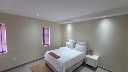 een witte slaapkamer met een bed en een raam bij Mafini Villa in Centurion