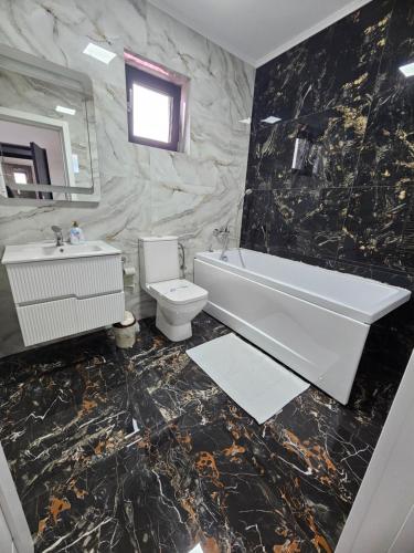 a bathroom with a tub and a toilet and a sink at Luxury LCF in Brăila