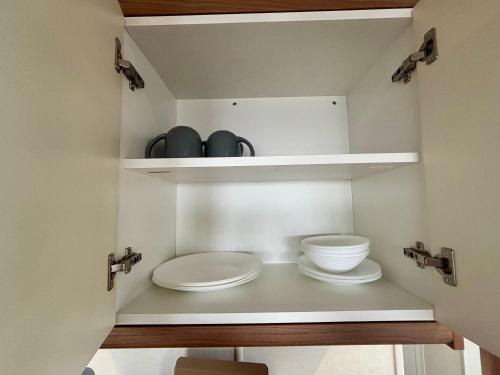 a bathroom with two white plates and bowls on shelves at Relax By The Coast - Spacious 6-sleeper Caravan in Leysdown-on-Sea